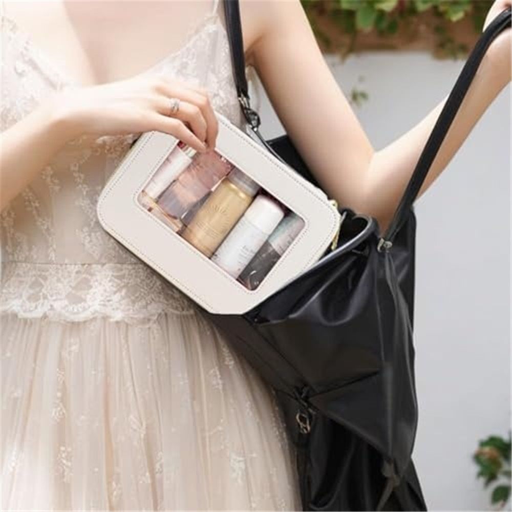 Cream makeup pouch with clear window carried in a handbag